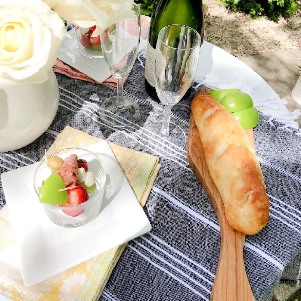 Jarcuterie and baguette on a charming round French cafe dining table in the garden - Hello Lovely Studio. #jarcuterie #frenchpicnic #frenchaesthetic #outdoordining