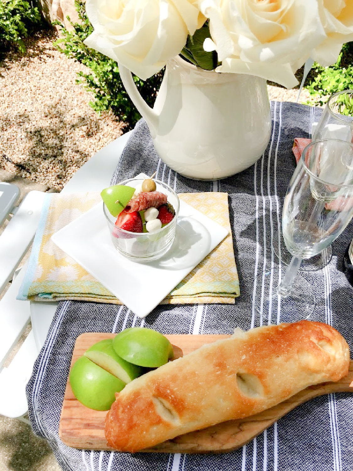 Jarcuterie and baguette on a charming round French cafe dining table in the garden - Hello Lovely Studio. #jarcuterie #frenchpicnic #frenchaesthetic #outdoordining