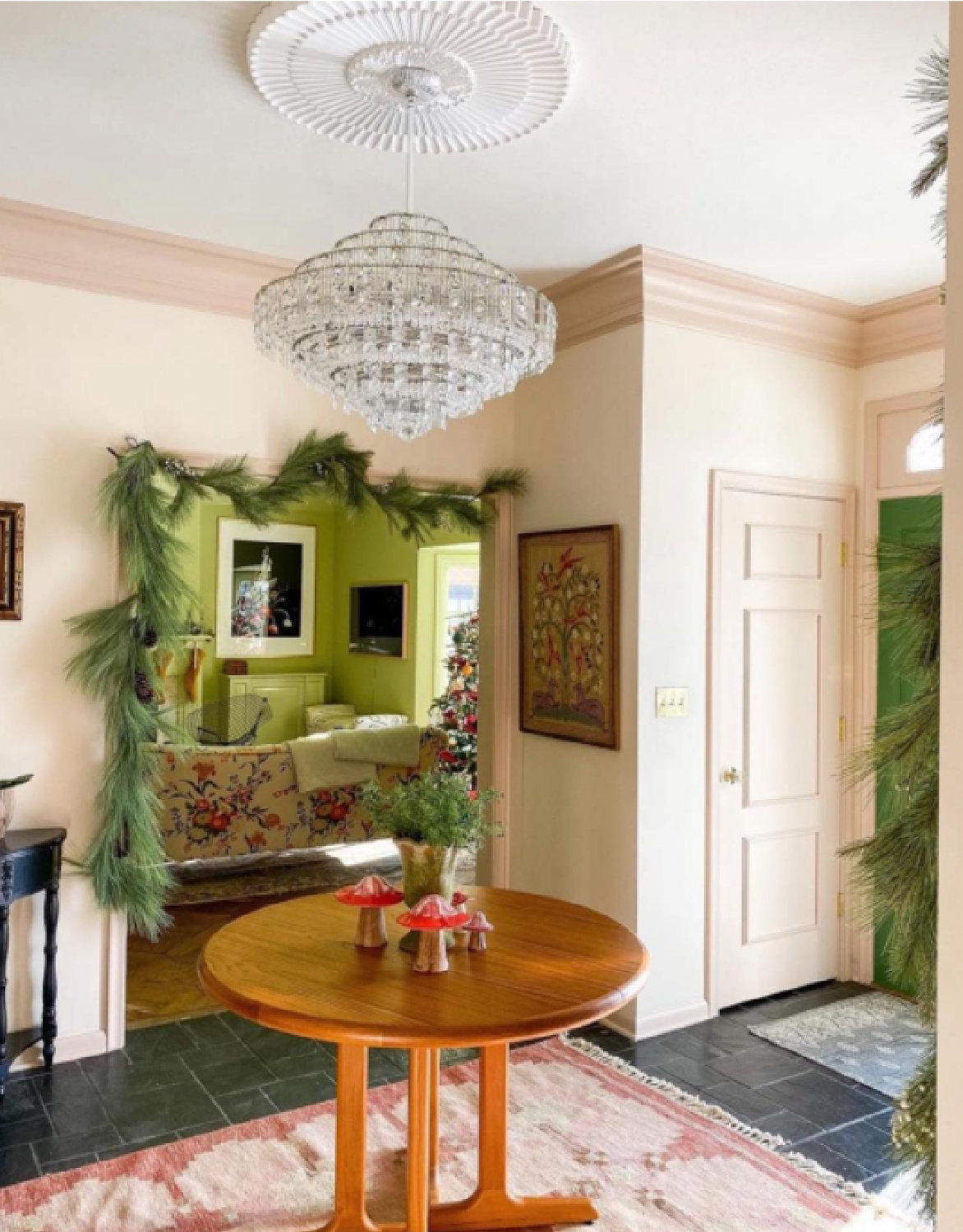 A glorious pink foyer with a magnificent crystal chandelier is decorated for the holidays - @witanddelight. #pinkrooms #classicinteriors #palepink