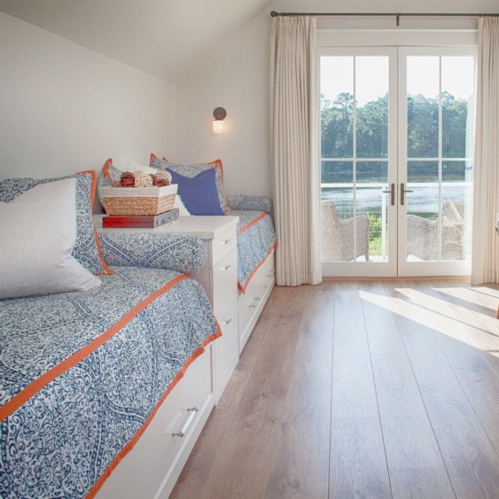 Blue bunk room in carriage house with built in beds, blue and white decor, bistro chairs, and wide plank wood flooring. Design by Lisa Furey. #bunkroom #captainsbeds #blueandwhite #bedroomdesign #coastalstyle