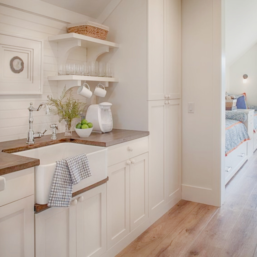 Kitchen with farm sink, wide plank wood flooring, built in captains beds and French doors to deck in carriage house with coastal and Shaker style. Design by Lisa Furey. #coastalstyle #modernfarmhouse #carriagehouse #interiordesign