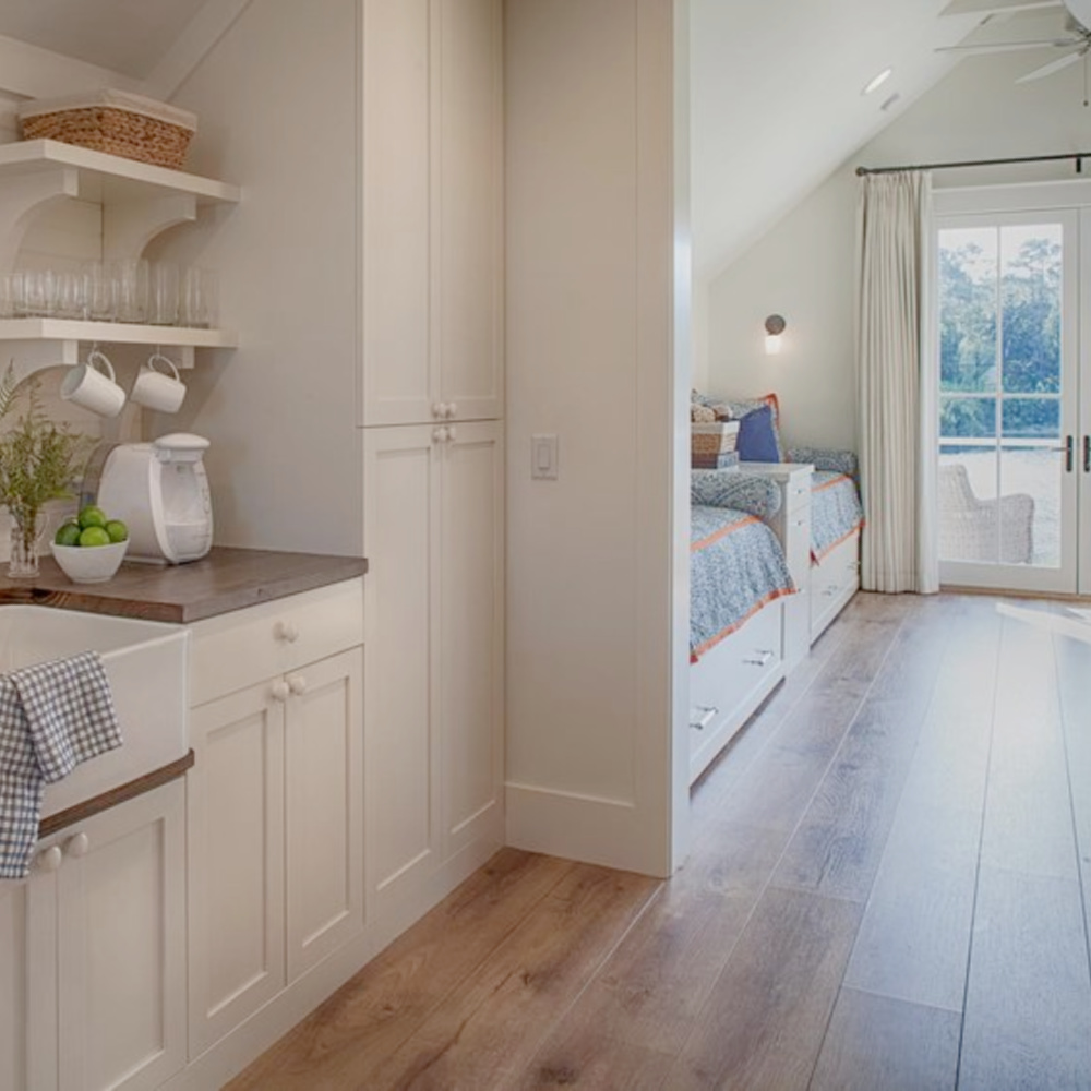 Kitchen with farm sink, wide plank wood flooring, built in captains beds and French doors to deck in carriage house with coastal and Shaker style. Design by Lisa Furey. #coastalstyle #modernfarmhouse #carriagehouse #interiordesign