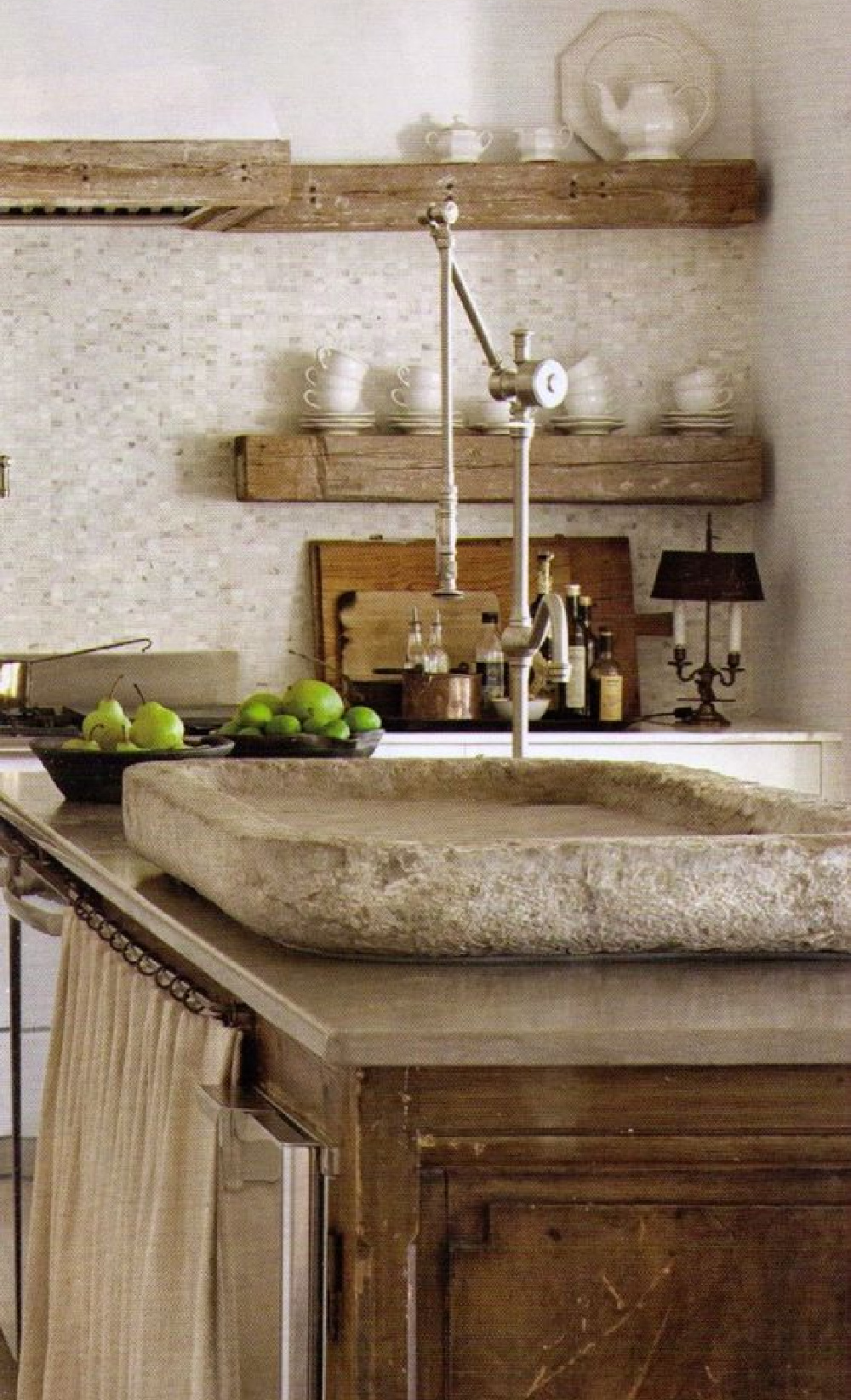 Luxuriously elegant and rustic French farmhouse kitchen with stone sink in island and rugged wood shelves flanking range - Shannon Bowers in MILIEU. #frenchkitchen #frenchfarmhouse