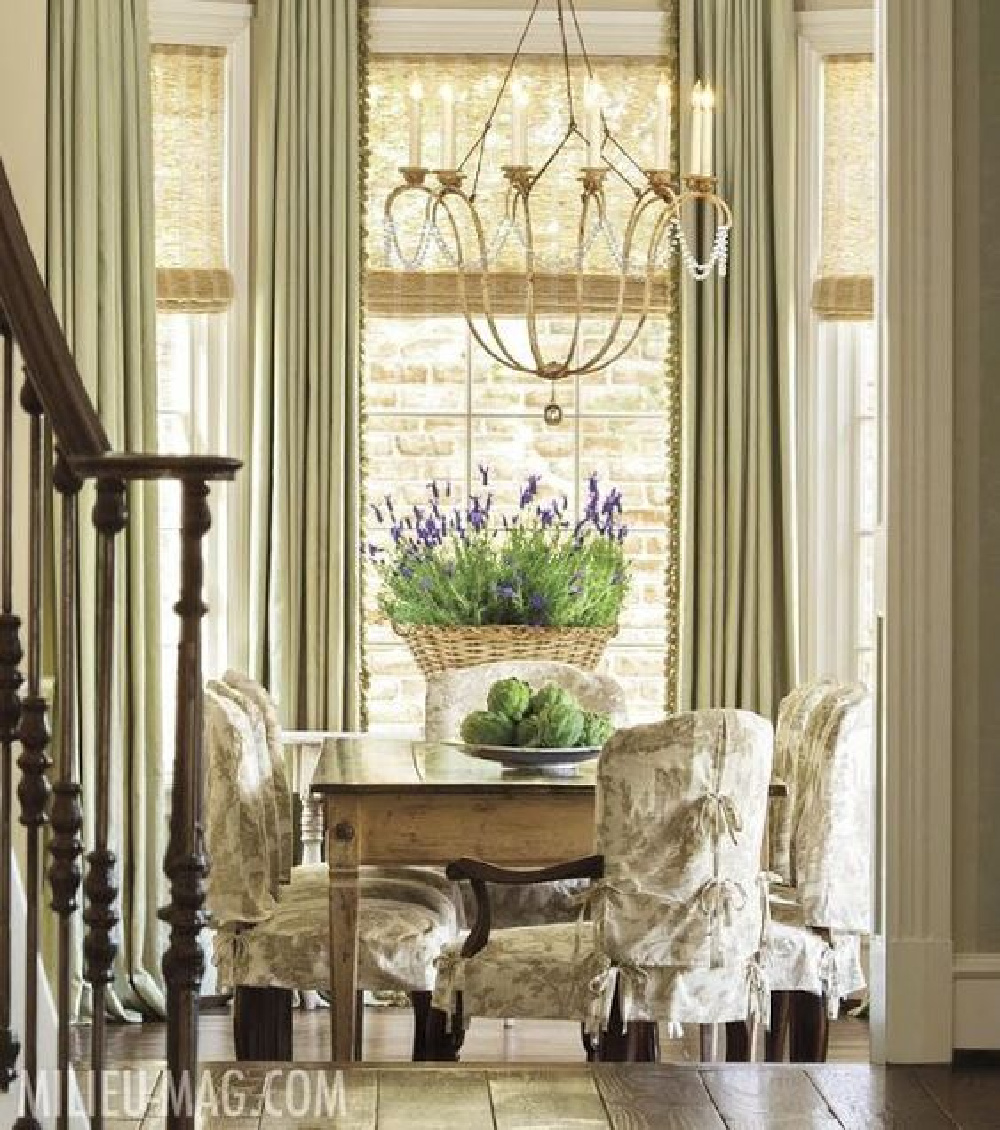 French country elegant dining area with farm table, toile slipcovered chairs, basket of fresh lavender and elegant chandelier - MILIEU. #frenchcountry #diningrooms