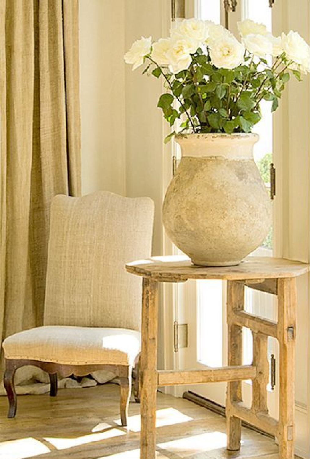 Pamela Pierce designed vignette with French antique confit pot with white roses, Belgian linen chair, and scrubbed natural wood pedestal - Milieu magazine. #pamelapierce #frenchcountry