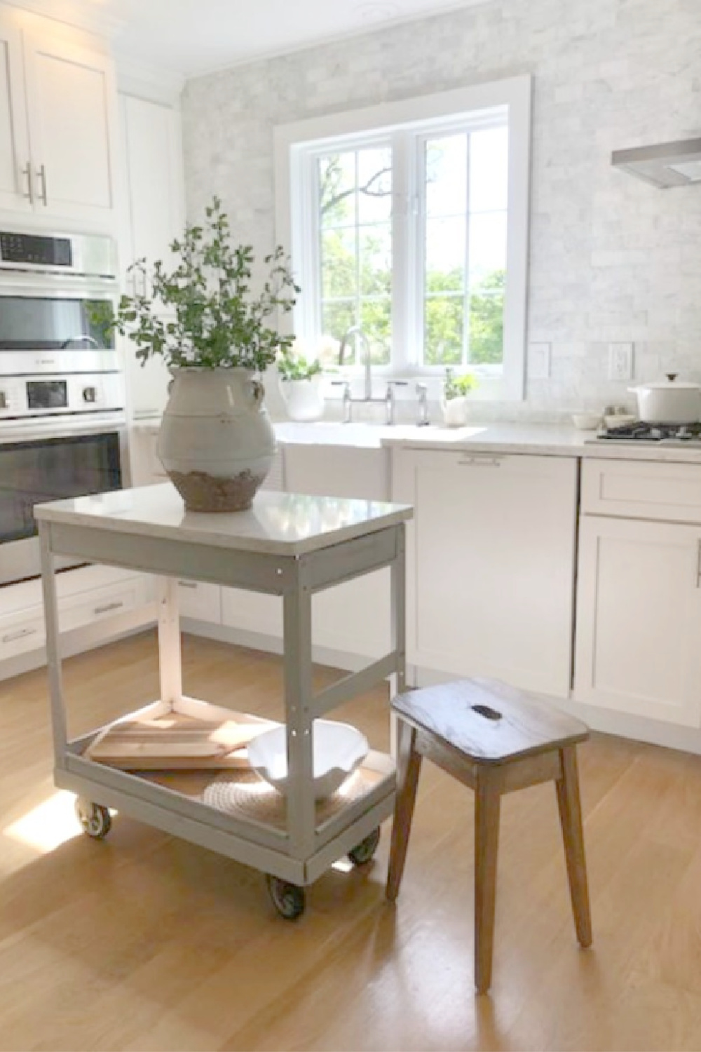 Hello Lovely Studio's serene white kitchen with an industrial cart repurposed as a work table. #whitekitchens #europeancountry #coastalkitchen #industrialcart