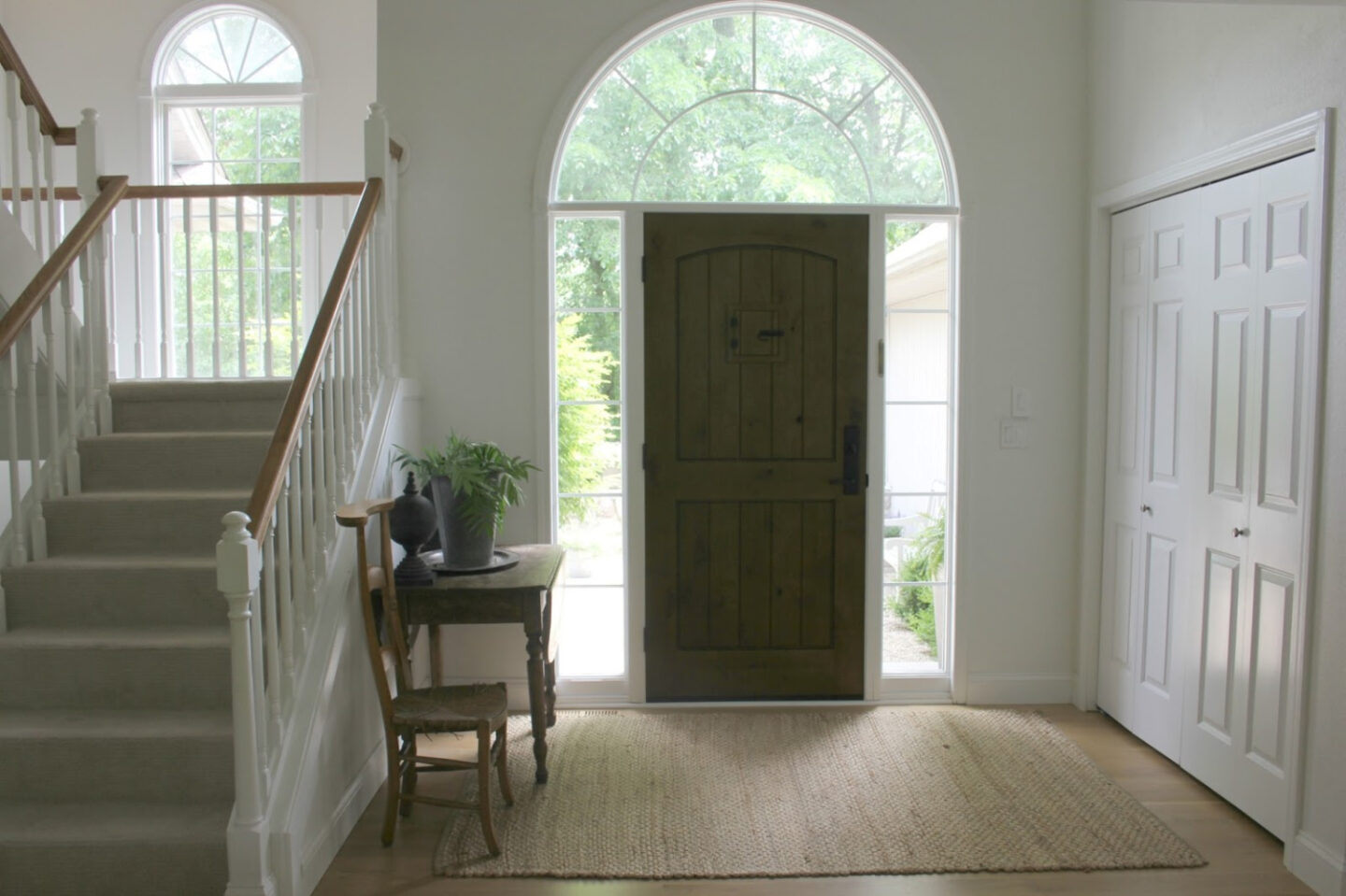 Front entry with knotty alder door, vintage table, and vintage French prayer chair - Hello Lovely Studio