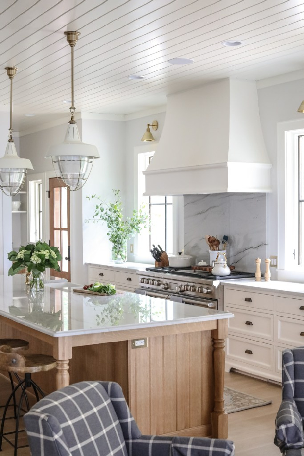 This gorgeous classic two-tone Shaker kitchen by Park & Oak features a custom range hood, wood stained island, white cabinets, and coastal pendants. #coastalkitchen #twotonekitchen #whitekitchendesign