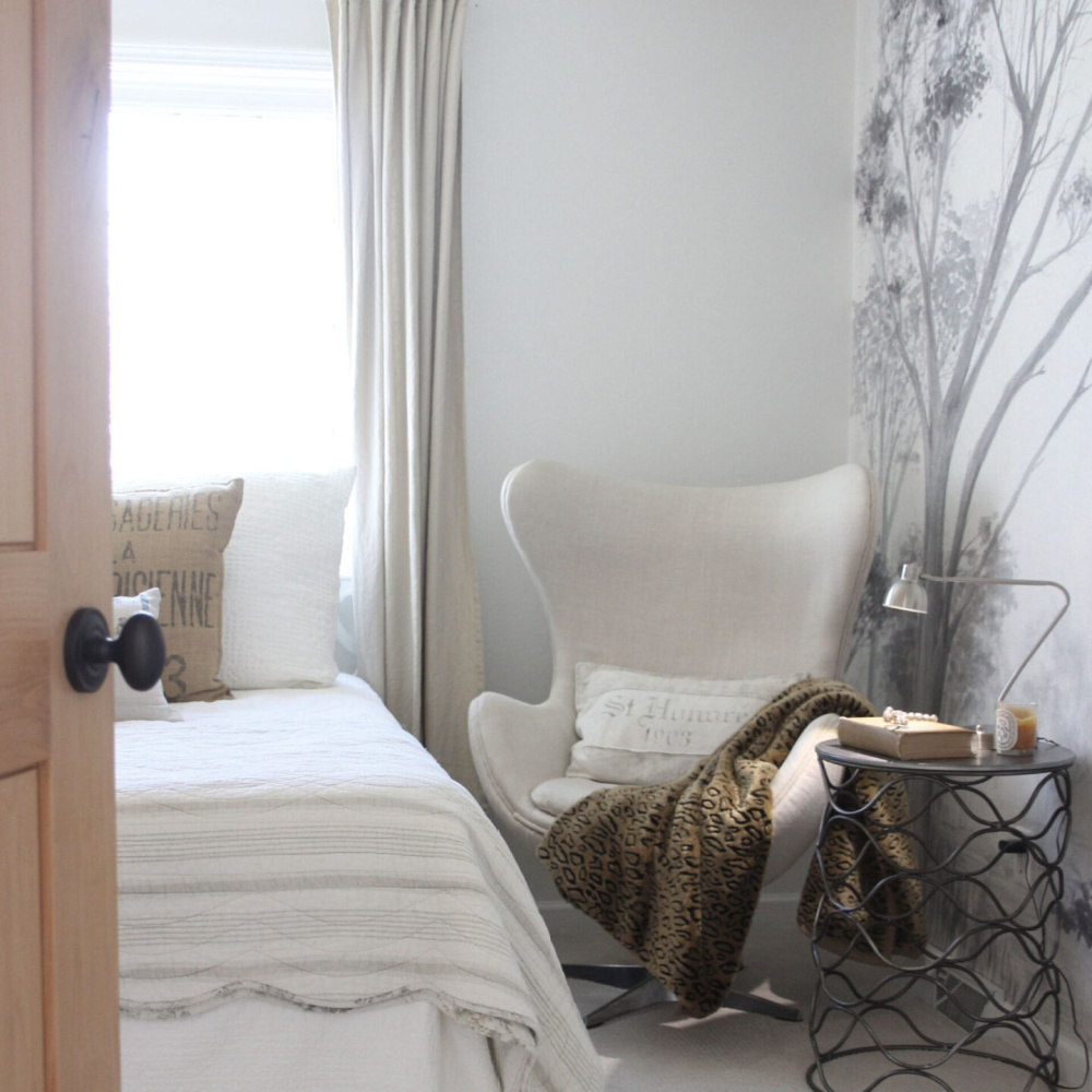 Alder door opens into a neutral bedroom with linen upholstered egg chair and grisaille mural on wall - Hello Lovely Studio.