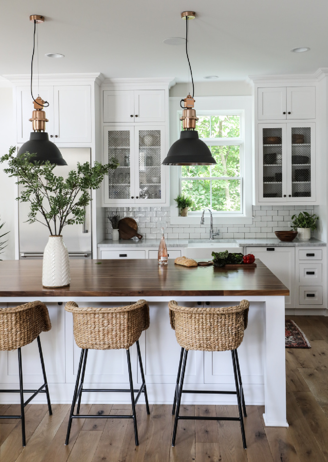 Simple yet sophisticated white modern farmhouse kitchen with wood topped island and rattan stools - Park and Oak. #classicwhitekitchen #whitekitchendesign #coastalkitchen #whiteoak #shakerkitchen