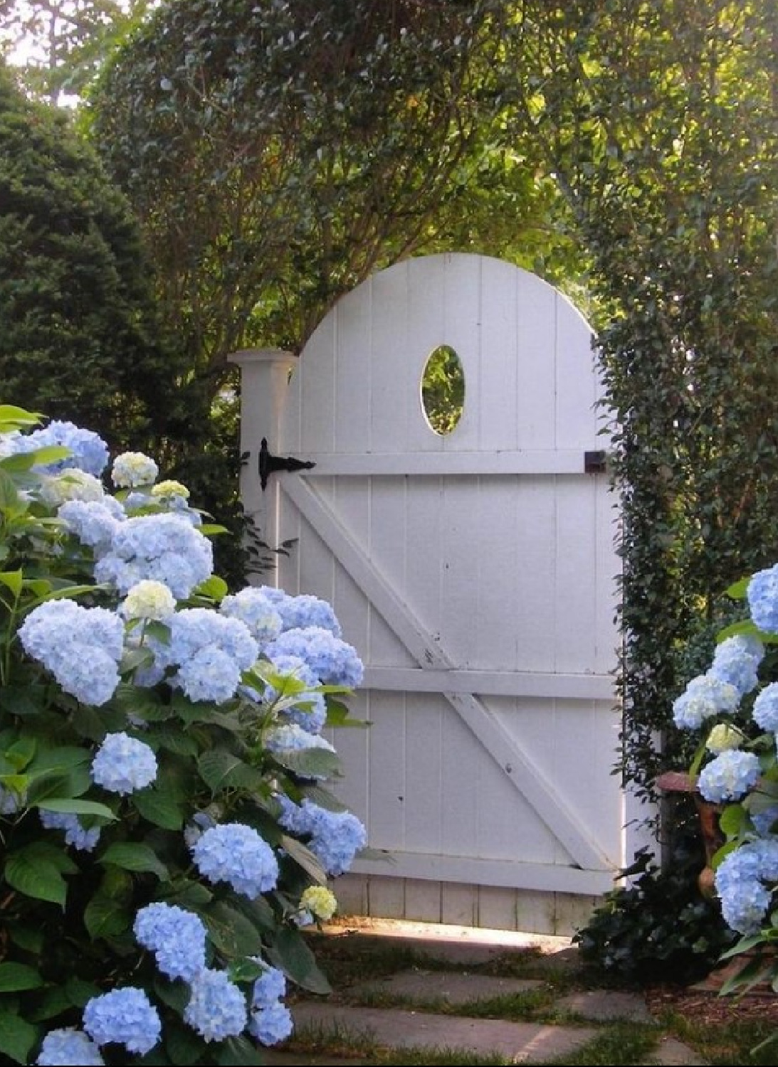 Hamptons style garden with blue hydrangeas and white wood arched wood gate - via Roman_And_Ivy. #hamptonsstyle #coastalstyle #coastalgarden #hamptonsgarden #easthampton