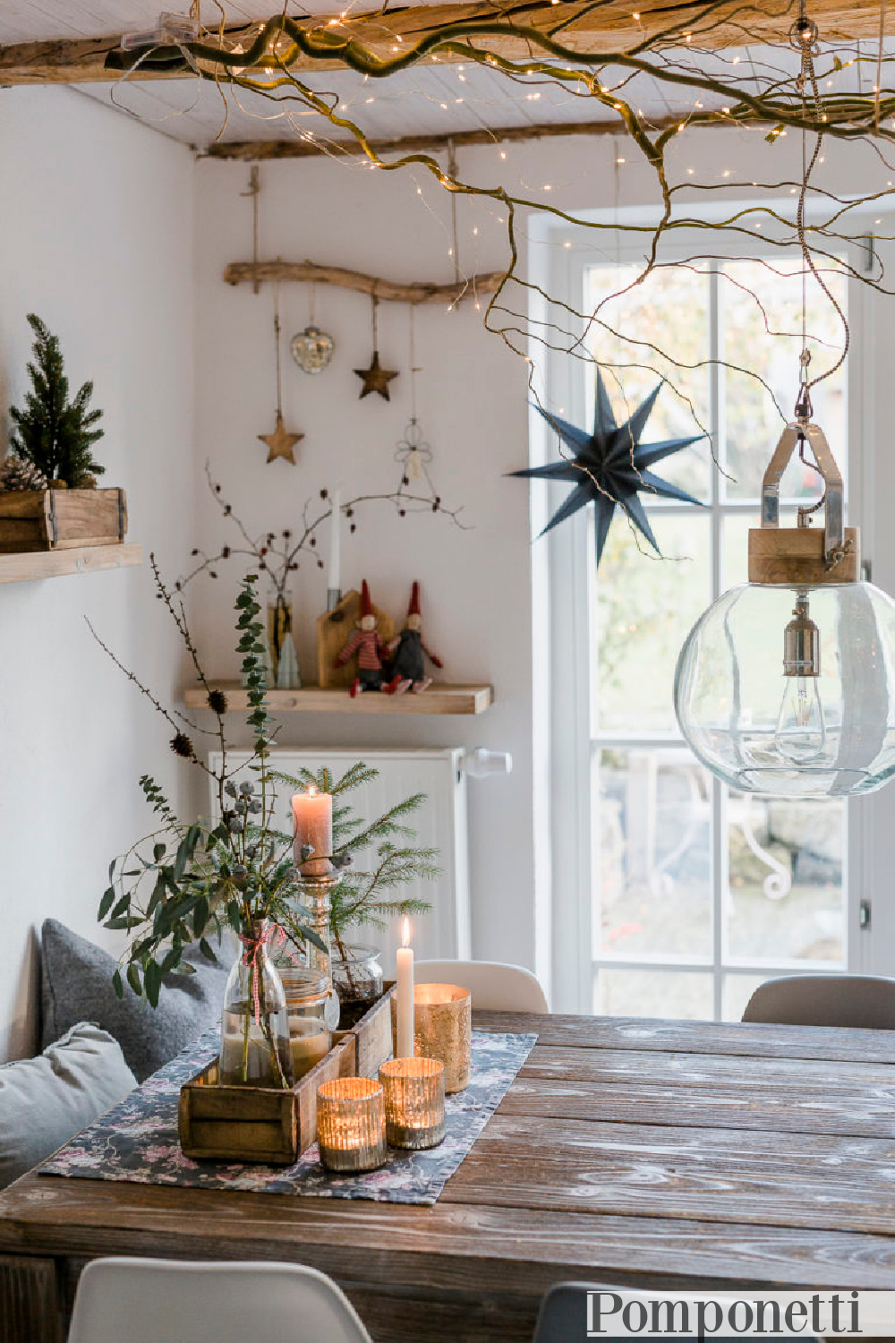 Scandi Christmas rustic decor in a dining area with driftwood, ornaments, branches, and white fairy lights - Pomponetti. #farmhousechristmas #christmasdecor #rusticchristmas #scandichristmas