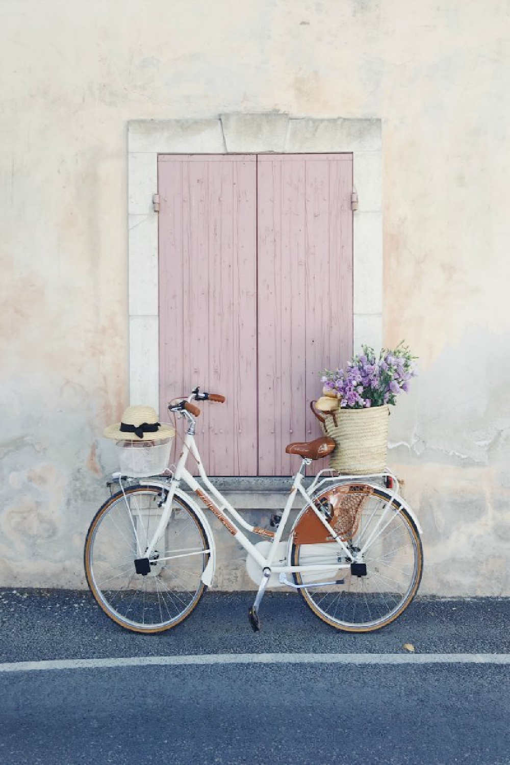 French market basket on a bicycle parked near blush pink shutters on a pale stucco home in France - Vivi et Marot. #provencestyle #blushpink #frenchcountry