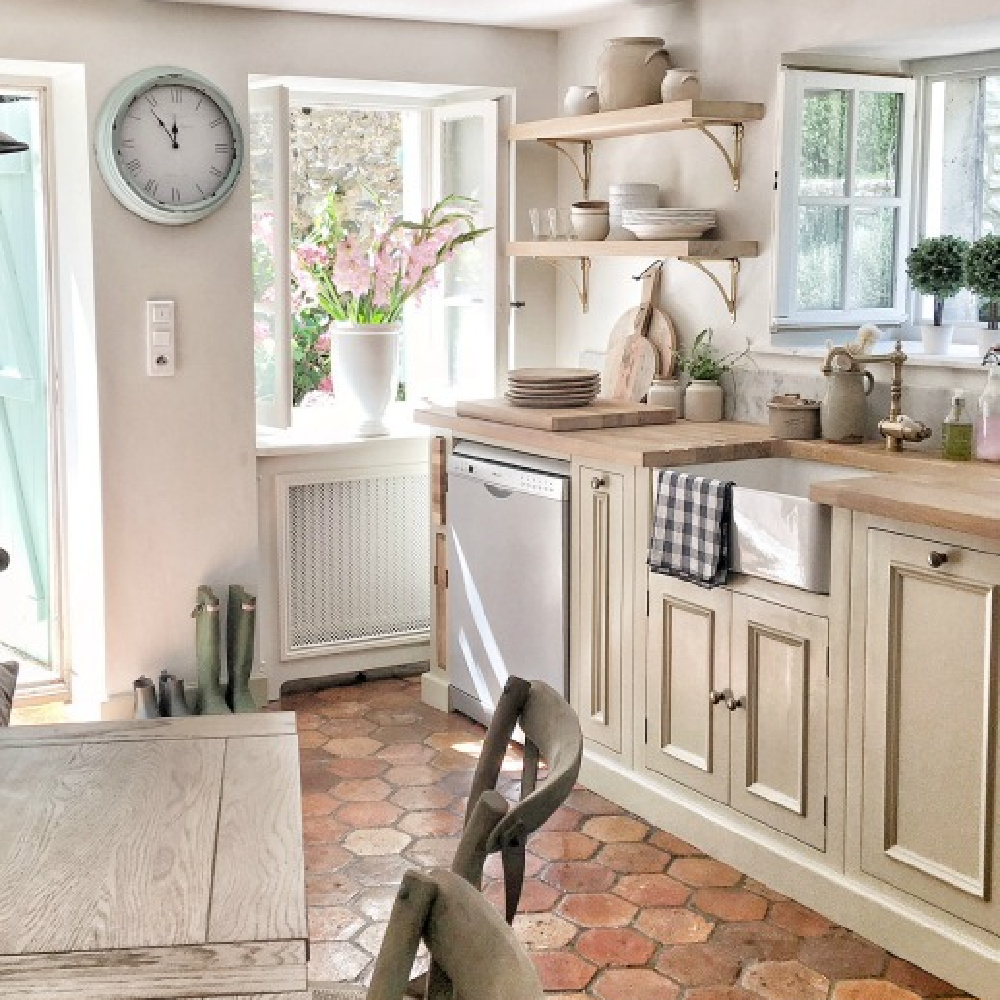 Rustic French farmhouse kitchen with beams, terracotta hex tile floor, putty cabinets, and traditional charm - Vivi et Margot. #frenchfarmhouse #kitchens