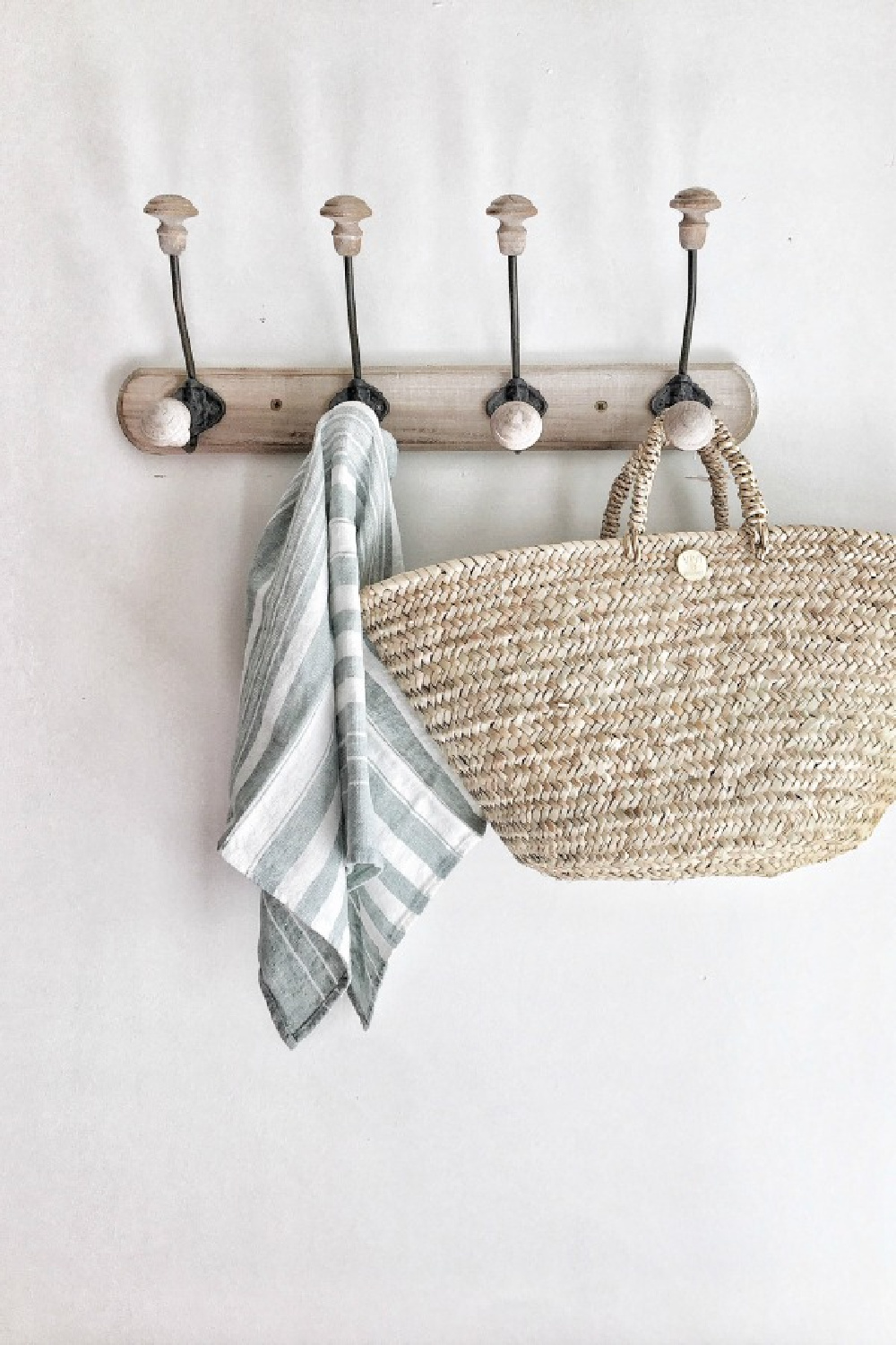French country hanging hook rack with stripe dishtowel and woven market basket.