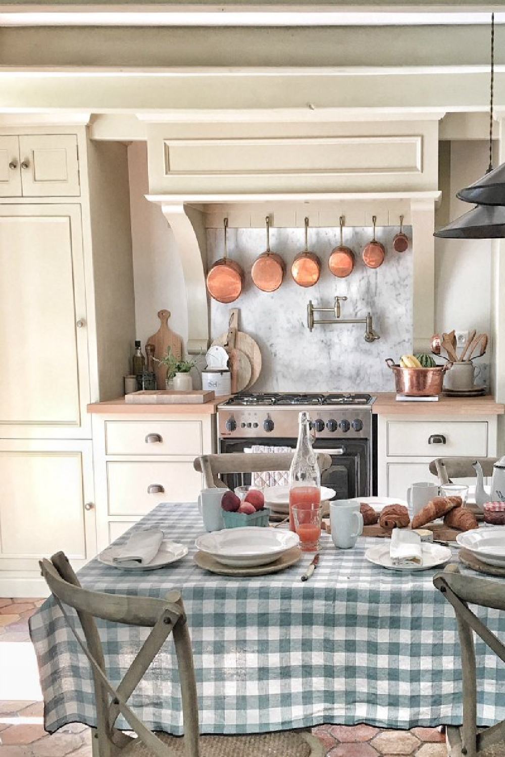 Rustic French farmhouse kitchen with beams, terracotta hex tile floor, putty cabinets, and traditional charm - Vivi et Margot. #frenchfarmhouse #kitchens