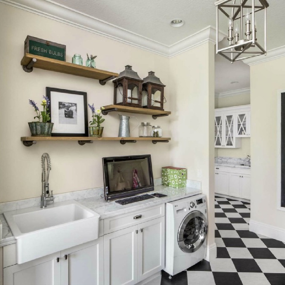 Traditional style laundry room with black and white check floor, farm sink, and decorative shelves - The Fox Group. #tratitionalstyle #laundryroom #interiordesign