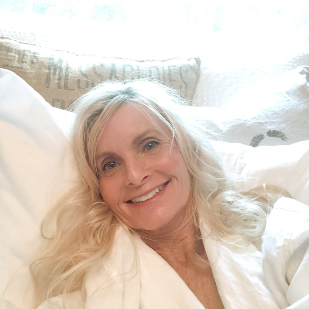 Michele of Hello Lovely Studio reclining on Nollapelli sheets in a white linen robe from Serena & Lily. #nollapellisheets #hellolovely #whitelinen #whitebedrooms