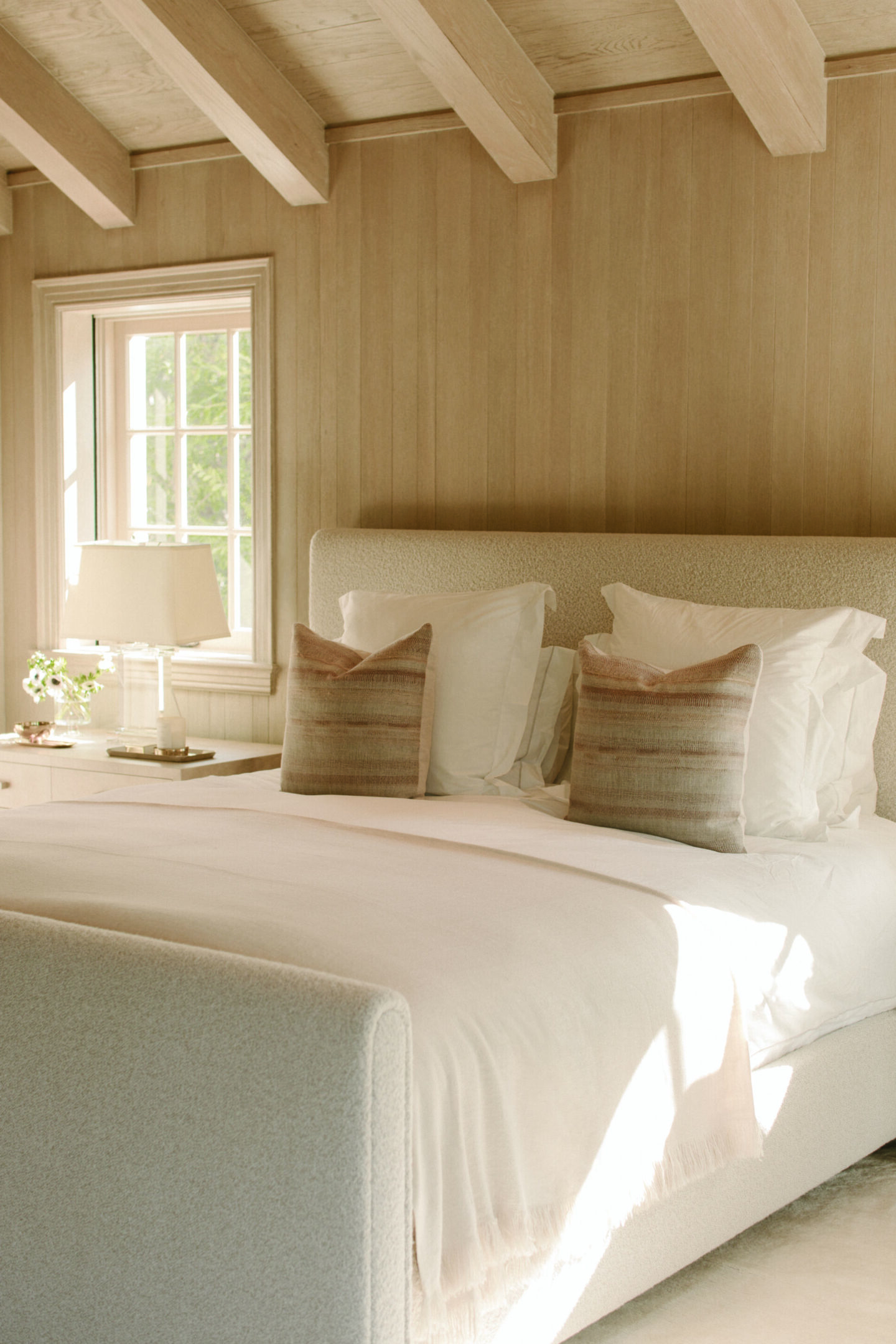 Emma Grede designed calm white bedroom with linen headboard in Pacific Natural at Home by Jenni Kayne. #pacificnatural #minimalbedroom #californiainterior