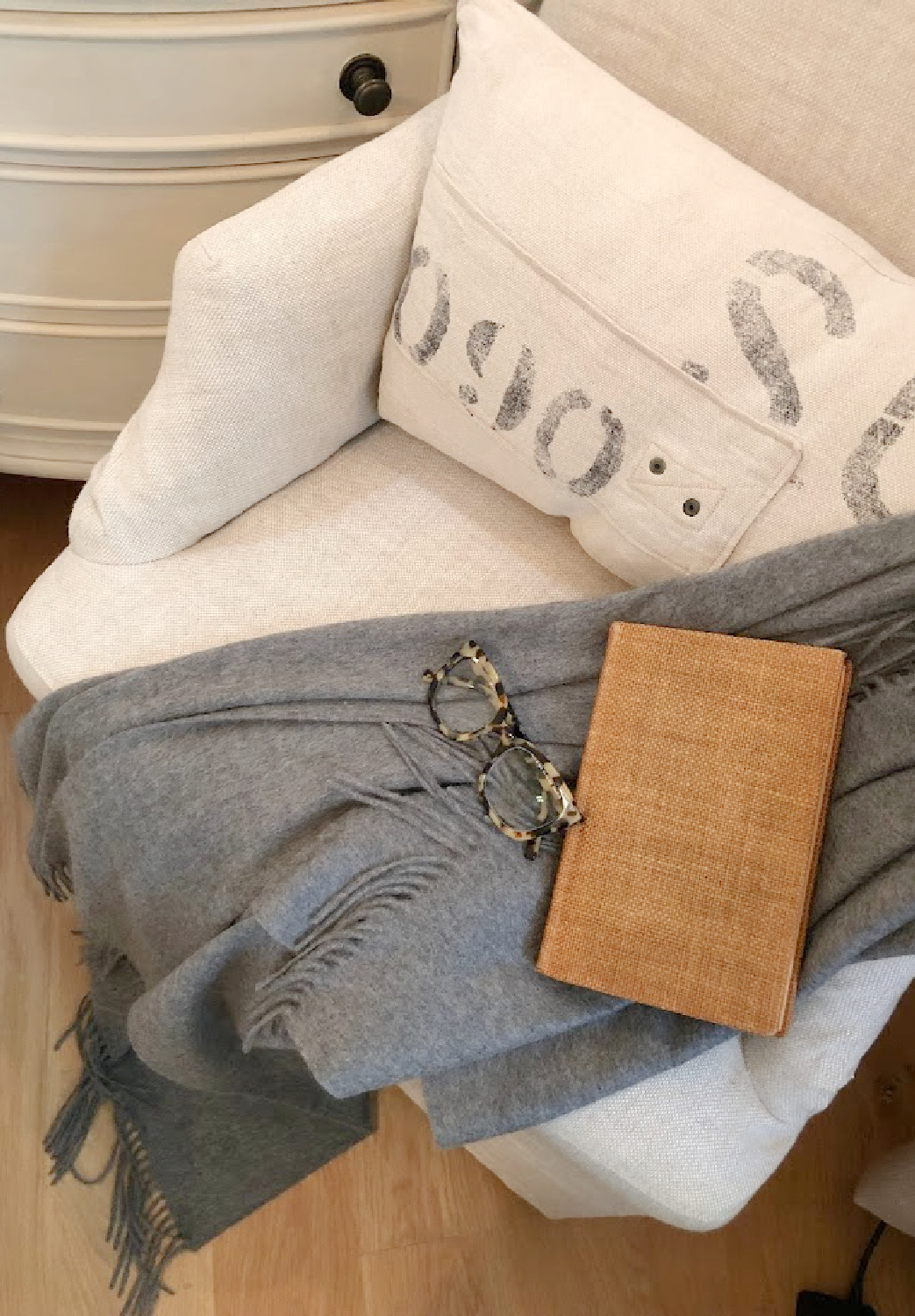 Warby Parker Aubrey frames for women on a dark gray cashmere throw on a linen chair in serene bedroom - Hello Lovely Studio.