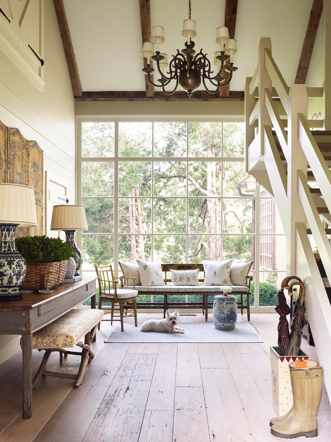 Timeless room with wall of windows, settee, console table, and Westie resting on a rug. From Melissa Penfold's LIVING WELL BY DESIGN.