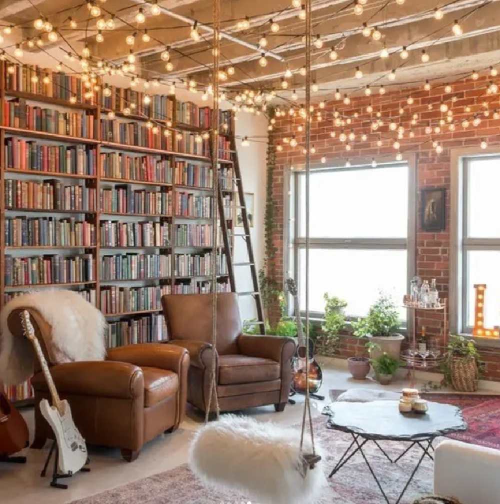 Cozy library nook with light strings at ceiling, swings with sheepskin, and leather club chairs - @behlerhomes. #cozynook #library #interiordesign #hyggeliving