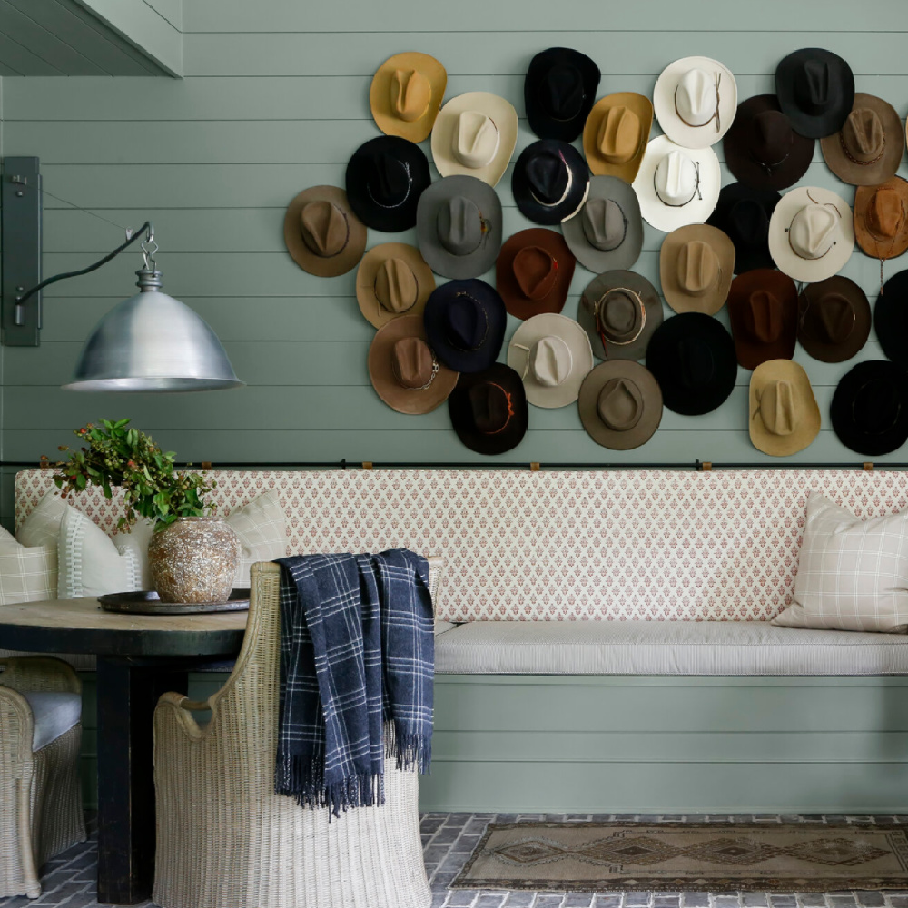 Green painted shiplap wall with whimsical hat collection (paint color: Acacia Haze) in a beautiful Southern home with design by April Tomlinson.