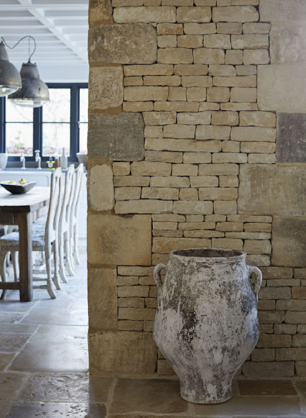 Rustic stone wall and ancient pot in a Cotswolds cottage by Anton & K.