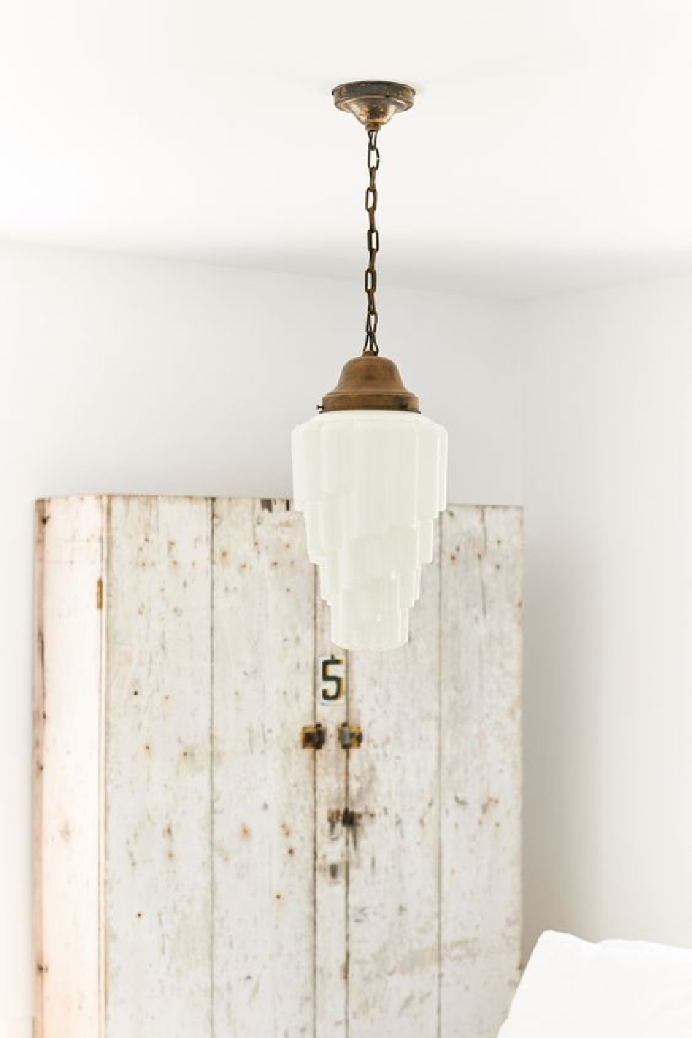 Leanne Ford designed bedroom with rustic white painted cabinet and vintage pendant.