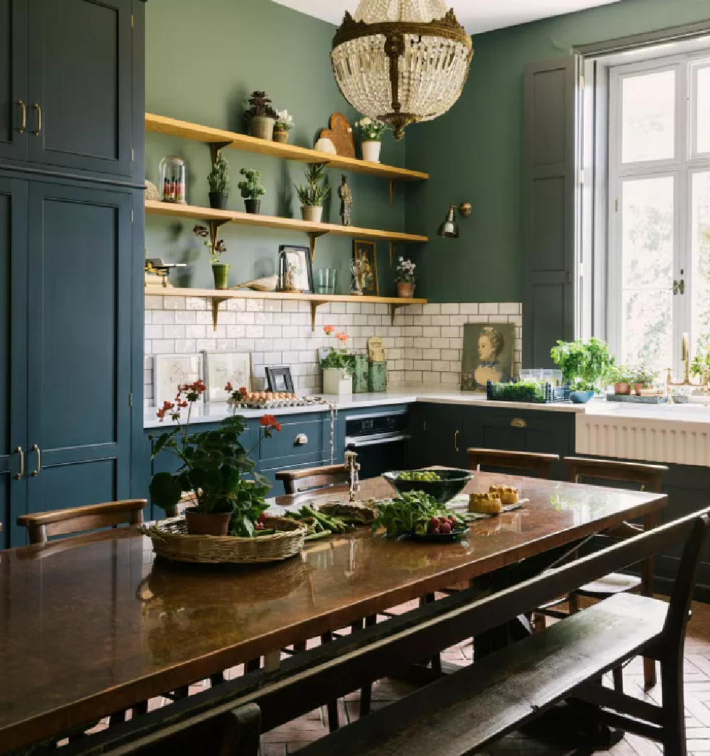 Bespoke English country kitchen with antique crystal pednant, farm sink, and long table with bench - deVOL.