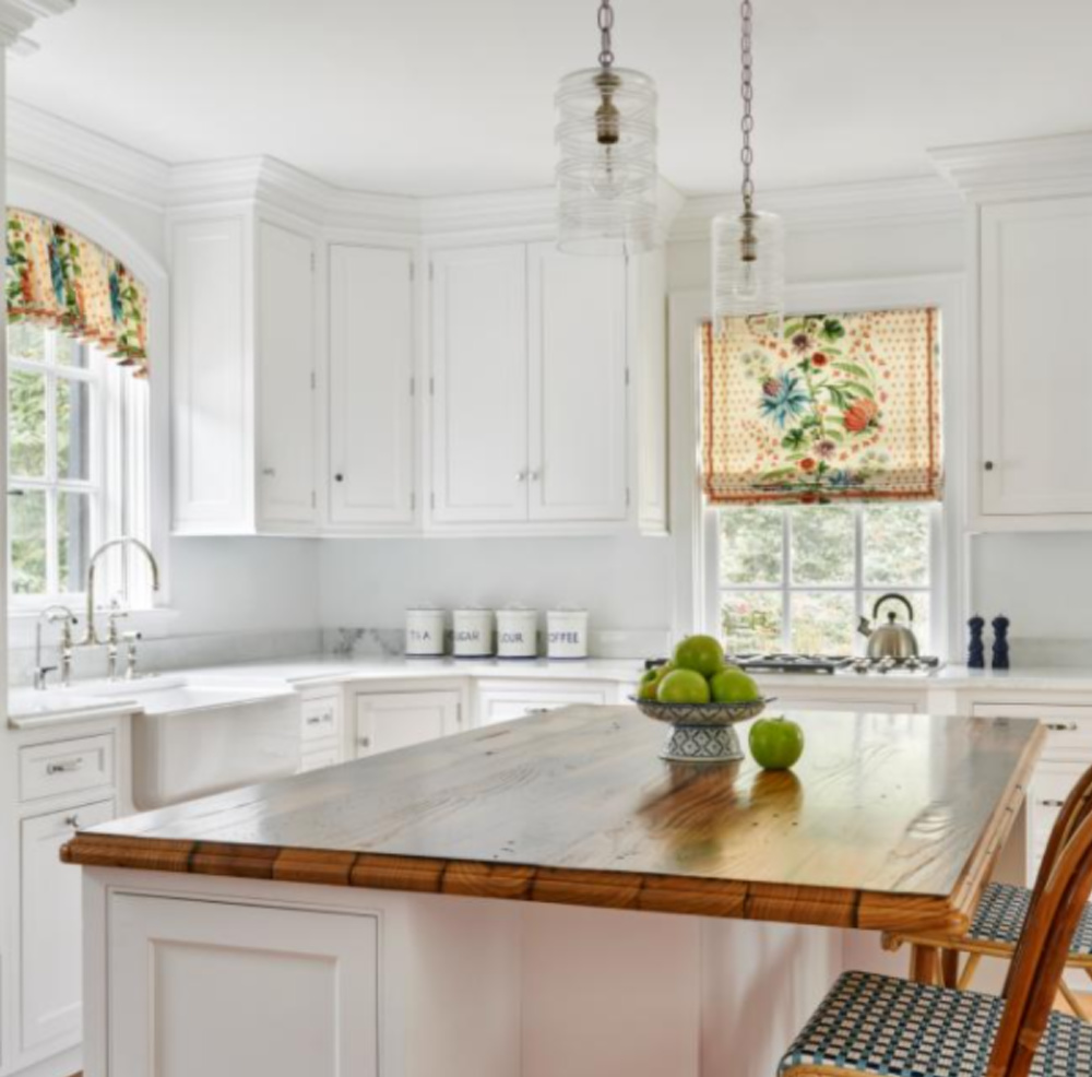 Serene white kitchen with colorful window treatments and farm sink - KDW Home Design.