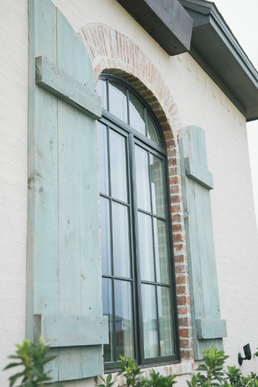 Country French rustic shutters painted Duck Egg blue flanking arched window on a new build home in Texas - Brit Jones.