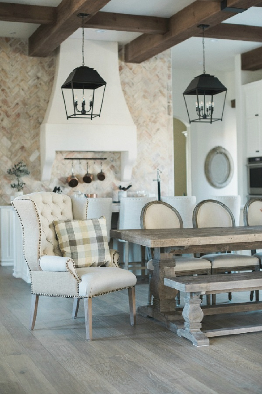 Country French kitchen with farm table, large lanterns, custom range hood, and Chicago brick statement wall - a new home with Old World style in Texas - Brit Jones.