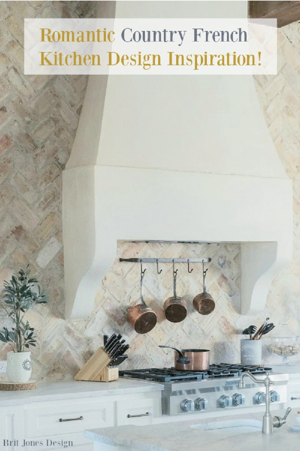 Chicago brick backsplash and custom French country range hood with copper pots on rack beneath in a country French kitchen by Brit Jones Design.