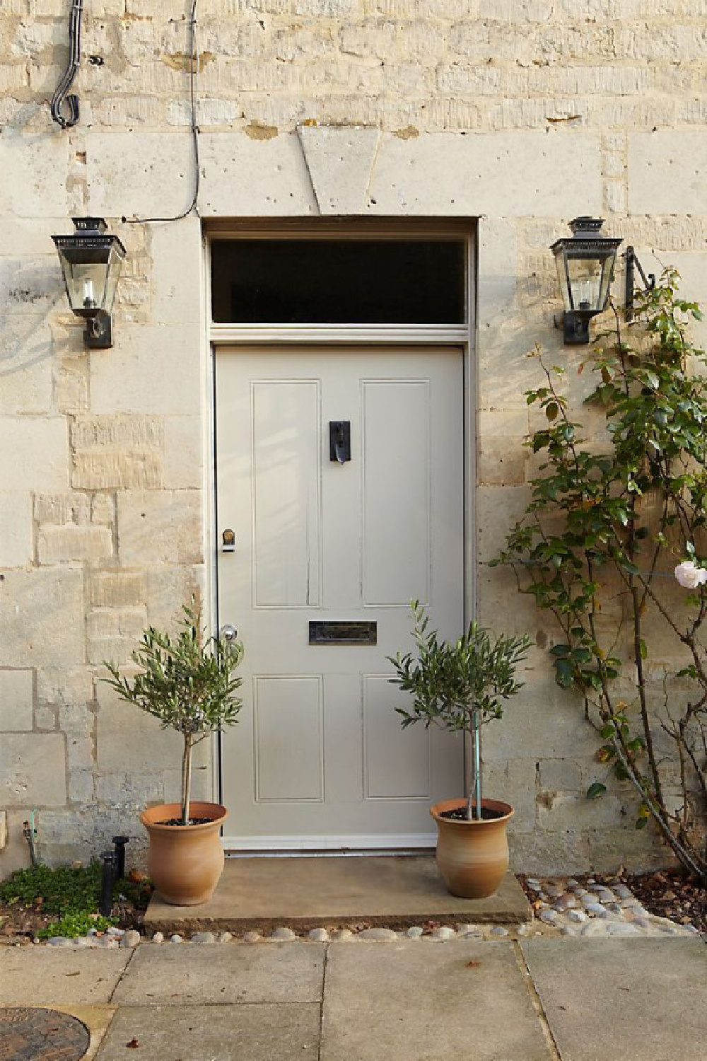 Stony Ground Farrow & Ball paint color is on this gorgeous front door of an English stone cottage with topiaries on porch. #paintcolors #stonyground #farrowandball #interiordesign #exteriorpaintcolors #frontdoorpaintcolor