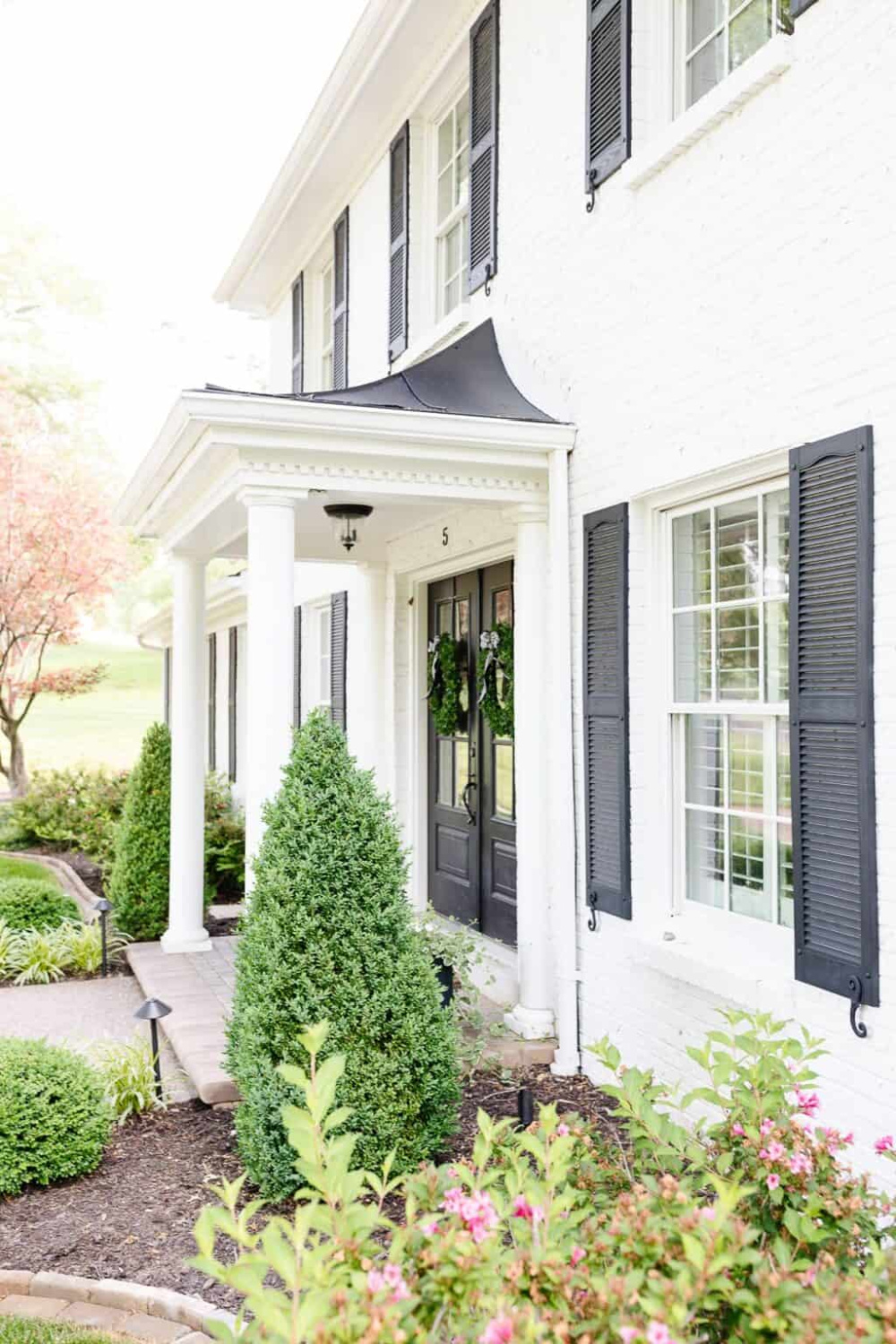 Simply White paint color (Benjamin Moore) on house exterior with black shutters - Julie Blanner. #simplywhitepaint #whitehouseexterior #paintcolors #housecolors