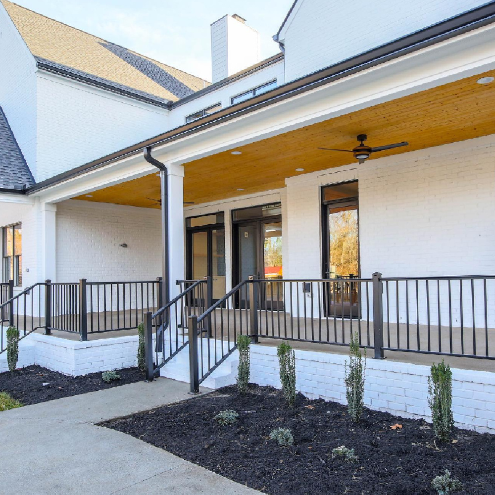 SW Pure White paint color on new brick house with black railings on porch with wood ceiling - @2kdevelopment. #swpurewhite #housecolors