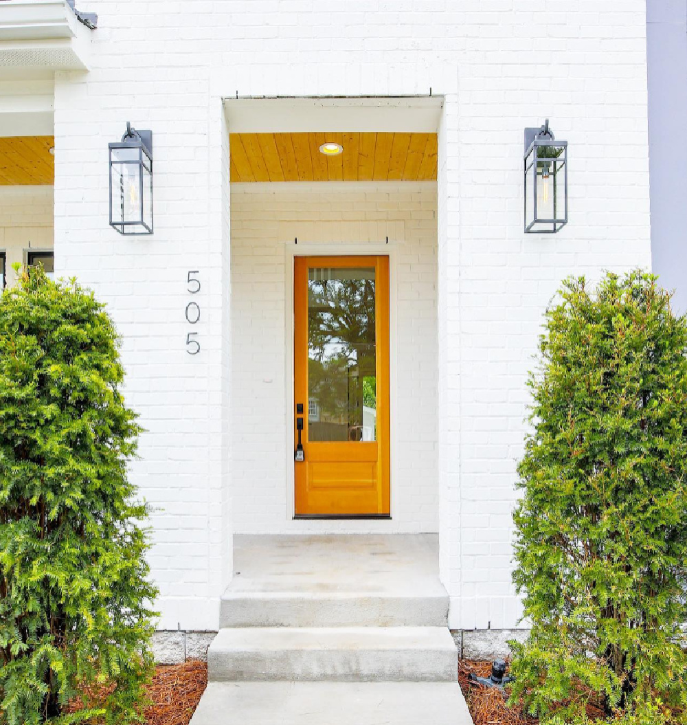 SW Pure White paint color on beautiful brick house with natural wood door and porch ceiling - @2kdevelopment. #swpurewhite #whitehousecolors #exteriorpaintcolors