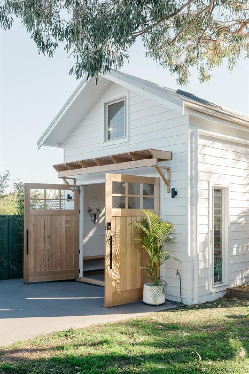 Exact paint color unknown - do try 
samples of BM Swiss Coffee and White Dove to start. Charming backyard beach cabana with double doors and white siding - Loughlin Furniture. #garageconversions #backyardshed