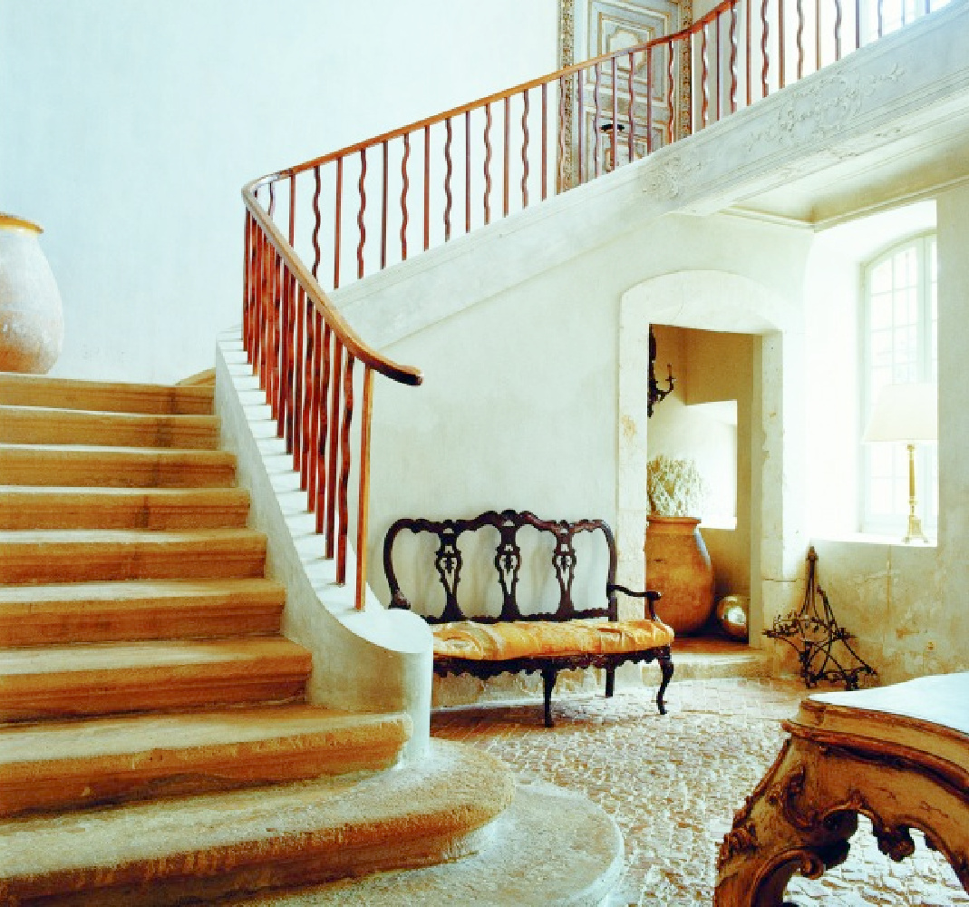 Breathtaking French country interior with sweeping staircase, plaster walls, stone floors, and Old World style - from La Vie Est Belle by Henrietta Heald. #frenchcountrystaircase #frenchinteriors #frenchfarmhouse