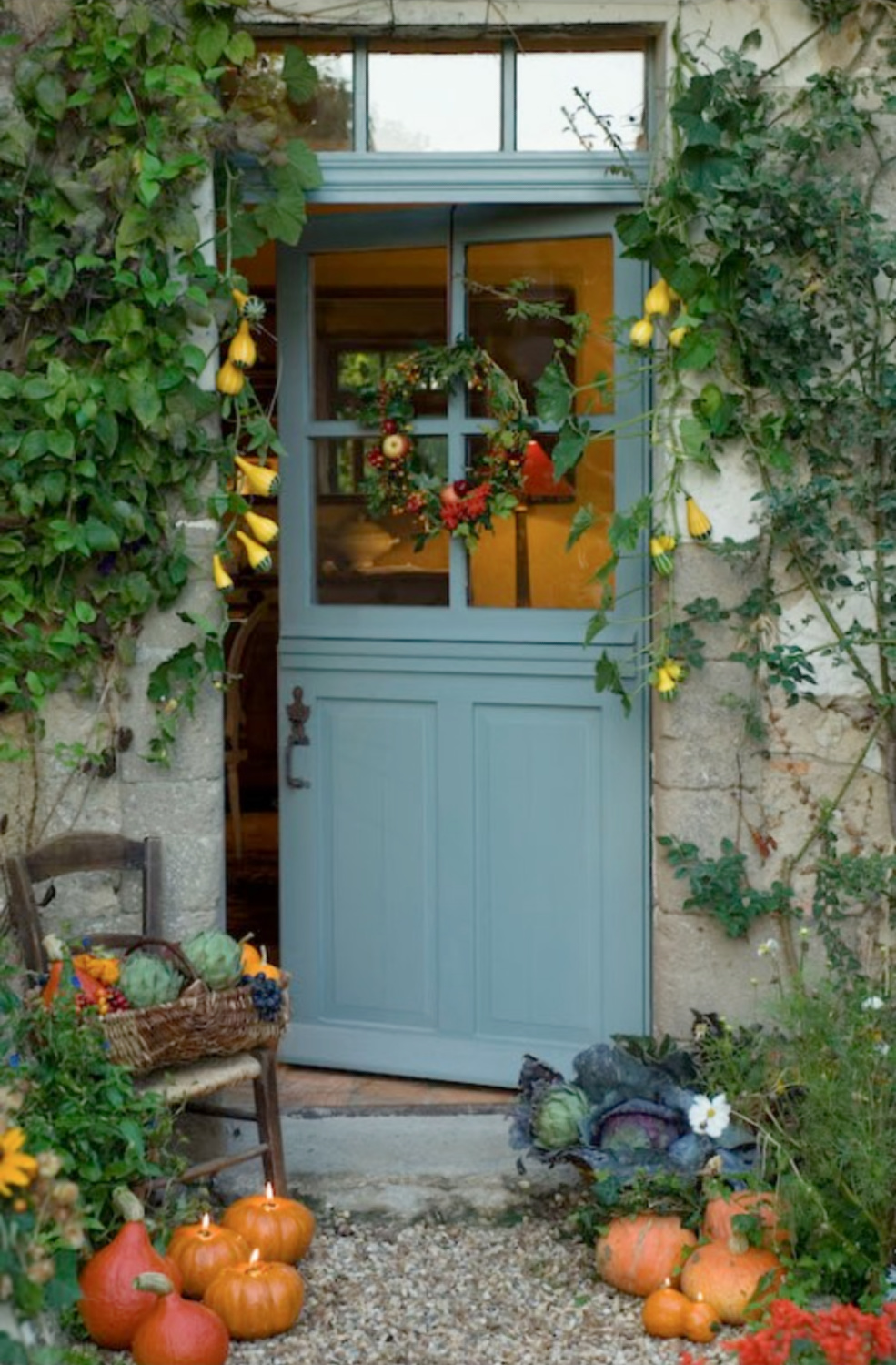 Charming blue French door with wreath as well as pumpkins and candlelight - Le Moulin Bregeon. #frenchcountryfalldecor #fallwreaths #frenchfarmhouse