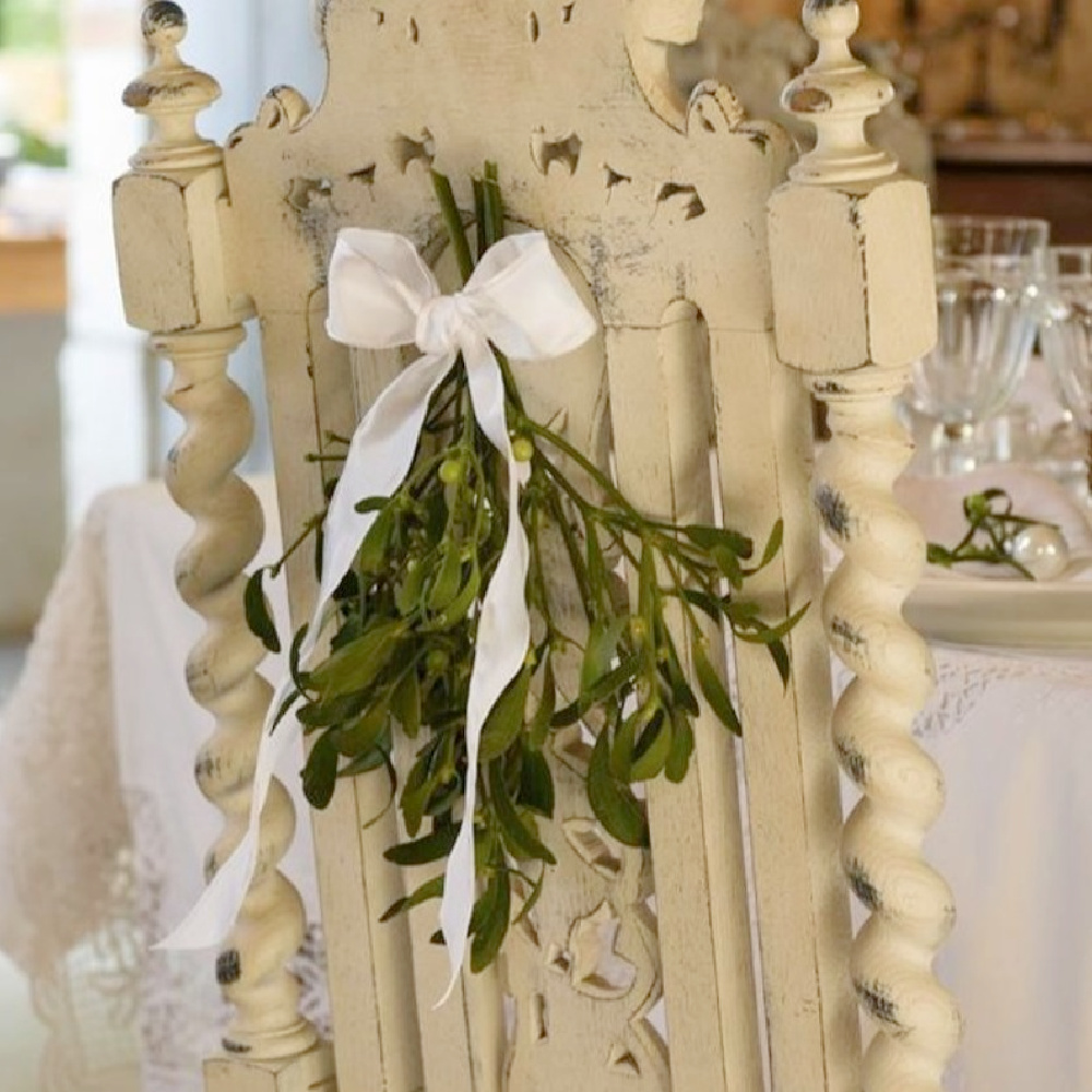 Simple and charming olive branch with white ribbon decor on back of dining chair - Le Moulin Bregeon. #frenchchristmas #frenchcountrychristmas