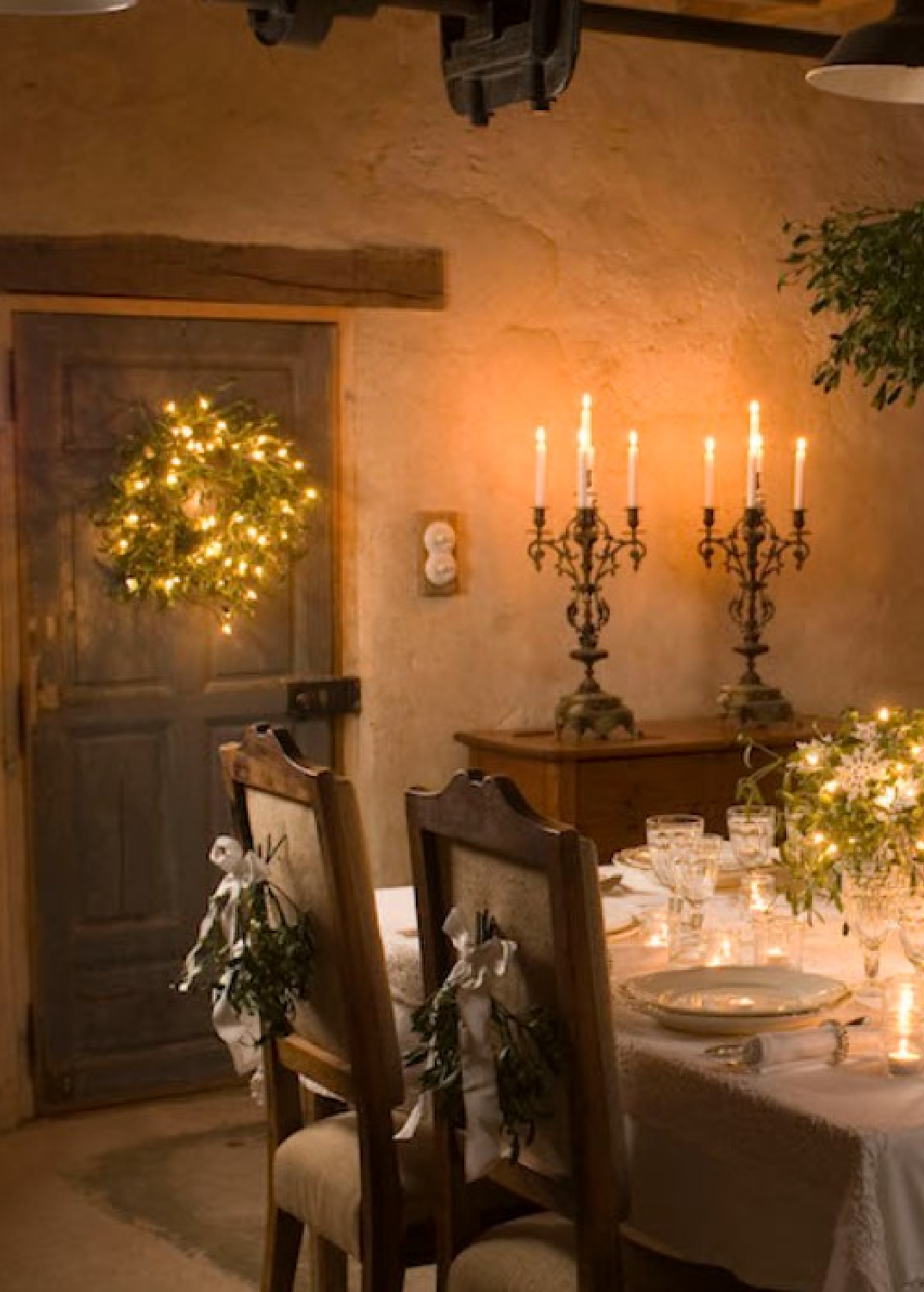 French Christmas dining table with candlelight, rustic stone walls, and traditional furniture - Le Moulin Bregeon. #frenchchristmas #frenchcountrydiningroom #holidaytables