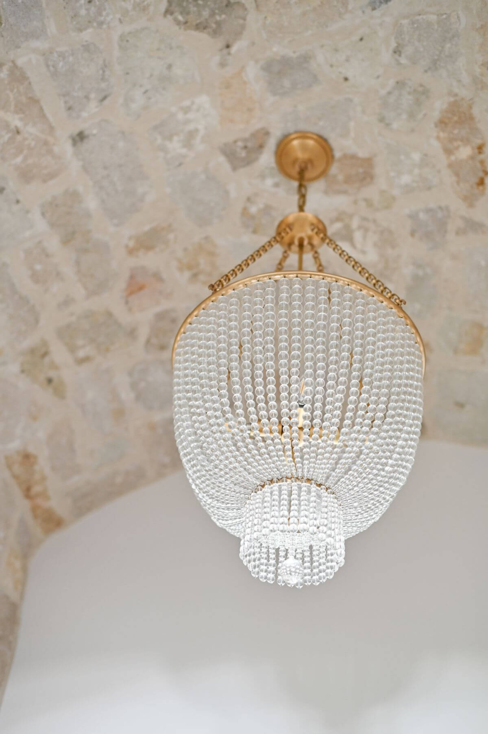 Beautiful crystal chandelier juxtaposed with a rustic stone ceiling in a French country foyer - Morningstar Builders. #frenchcountryfoyer #crystalchandeliers