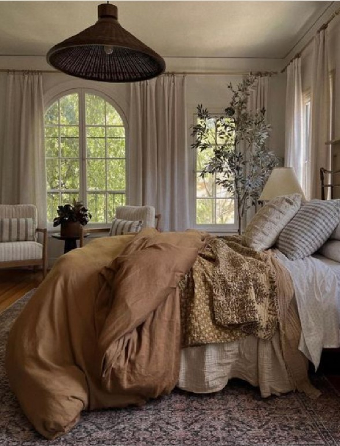 Gorgeous bedroom designed by Amber Lewis with arched windows, sumptuous bedding, and rattan pendant light. #californiachic #bedroomdesign #liveableluxury #modernrusticdecor