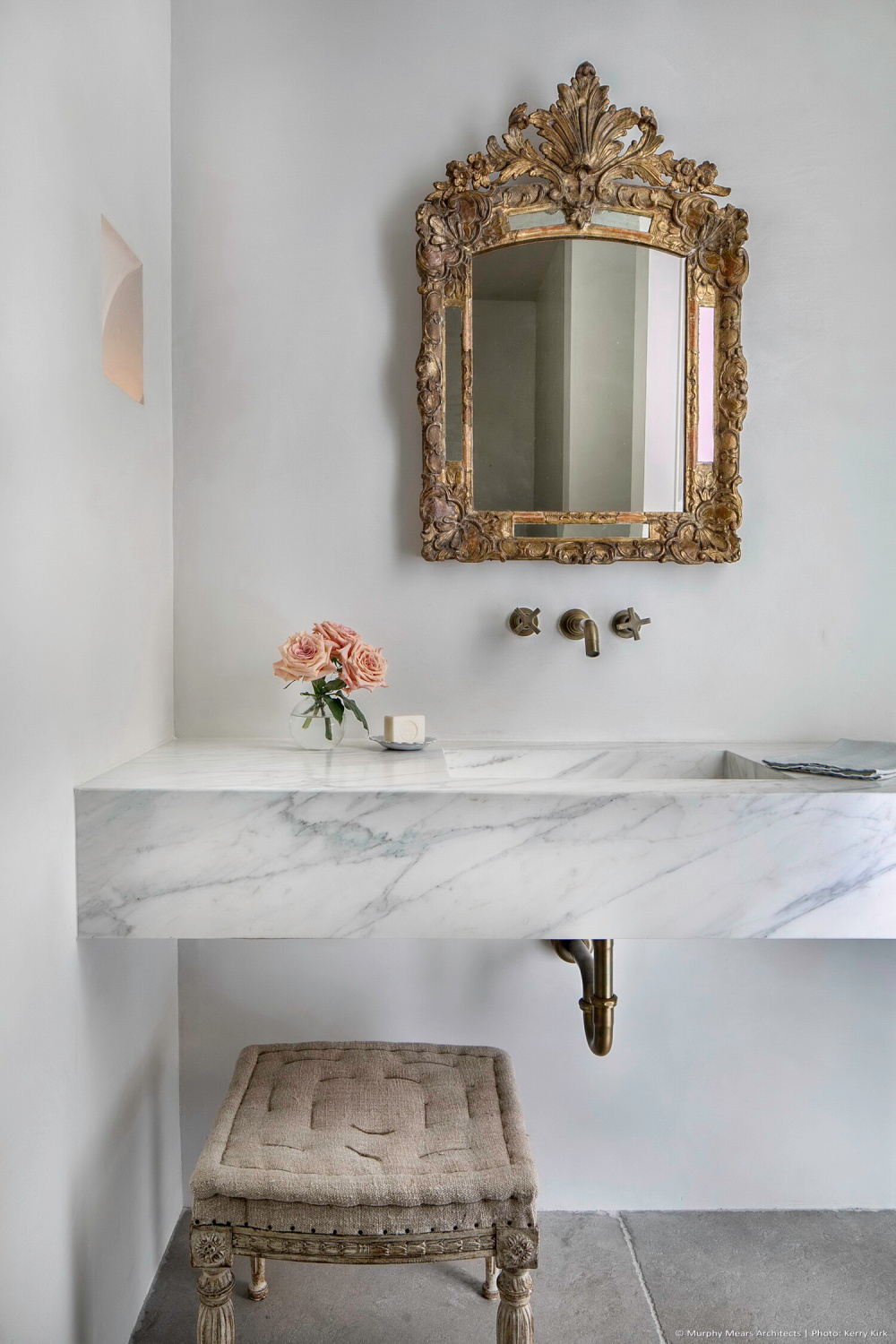 Elegant white marble vanity in a modern French bath with gold finishes, wall mount faucet and design by Jill Egan. #modernfrench #bathrooms