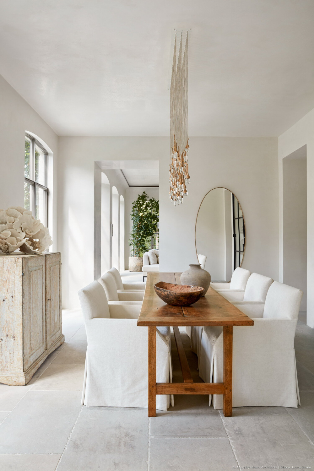 Modern French dining room with antique farm table, Swedish apothecary chest, and crystal chandelier by Ochre. #modernfrench #diningrooms