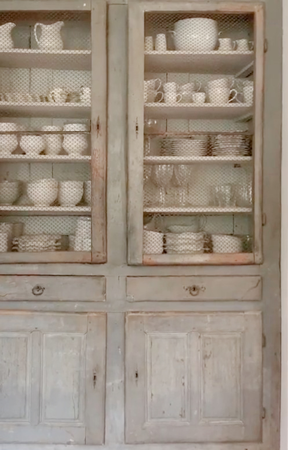 White French farmhouse dishware in an old blue-grey antique cupboard with chicken wire doors at Patina Farm - Velvet and Linen. #frenchfarmhouse #europeanantiques #frenchkitchen