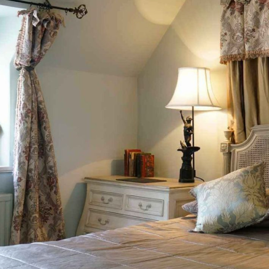Romantic Cotswolds cottage bedroom with a drapes and canopy above bed.