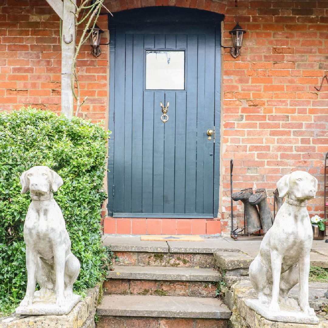 Charming arched front door and dog statues at a Cotswolds cottage. #cotswoldscottage #englishcountry #vacationcottage